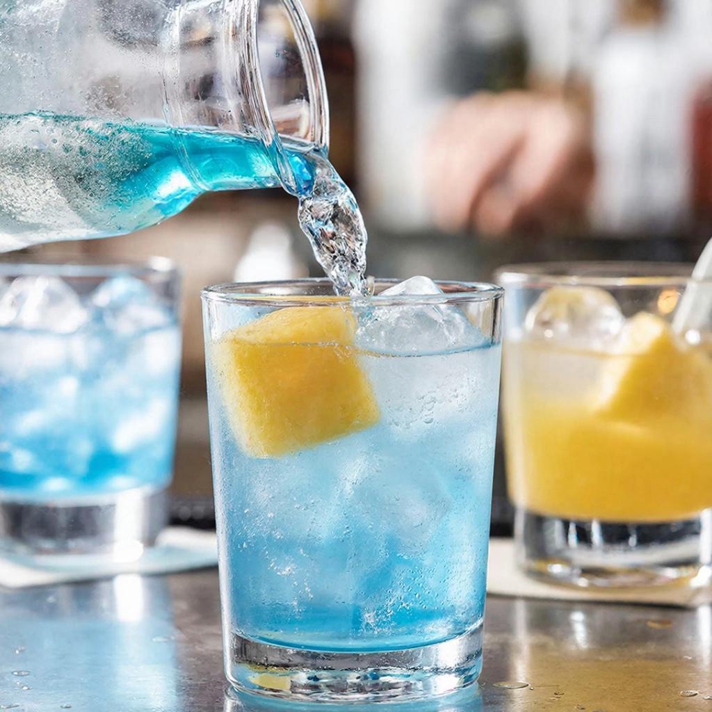 Сборка Голубой лагуны Приготовление коктейля Голубая лагуна в бокале со льдом и сиропом блю кюрасао